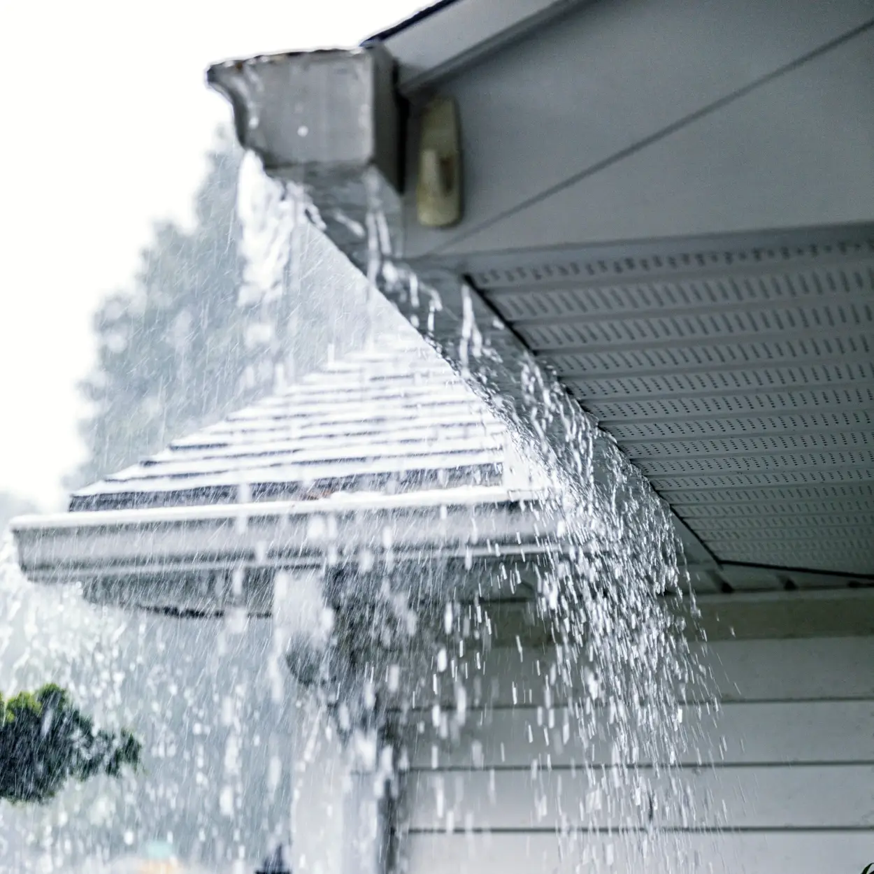 Residential gutter with water overflowing during rainstorm.