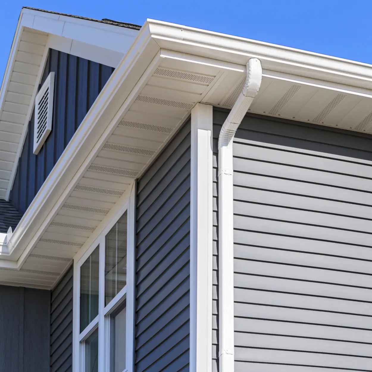 Residential home exterior and gutters with blue sky in the background.