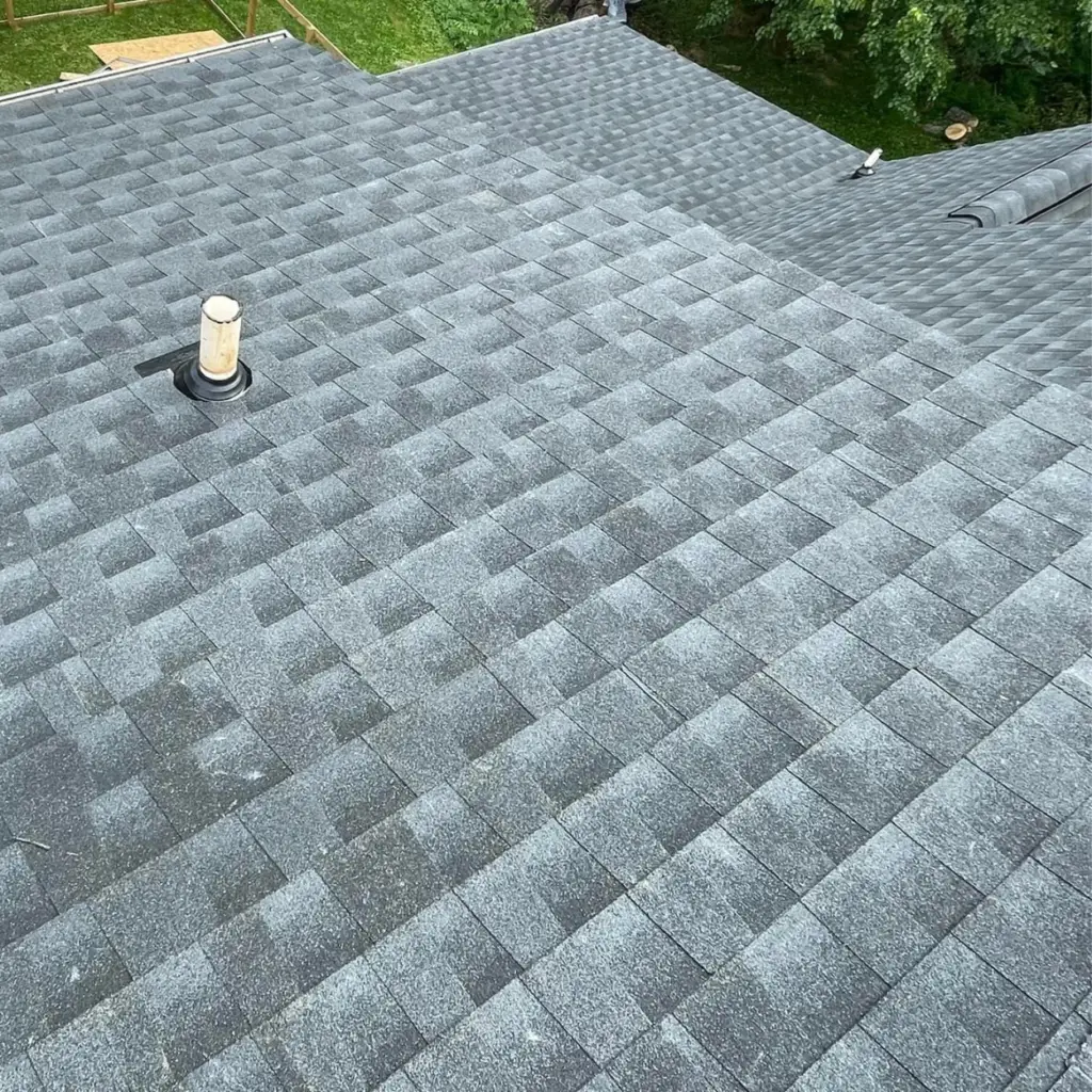 Newly installed asphalt shingle roof with a residential back yard in the background.