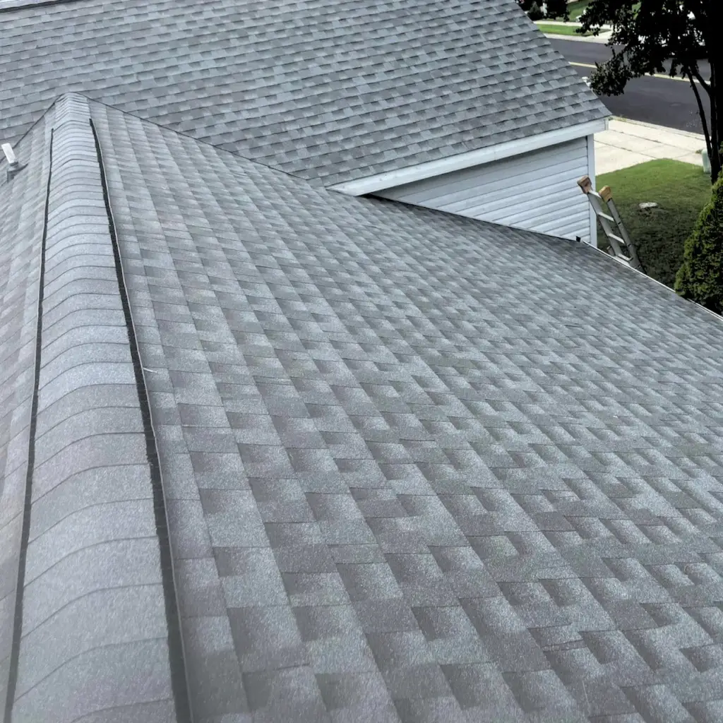 Newly installed asphalt shingle roof with a residential front yard in the background.