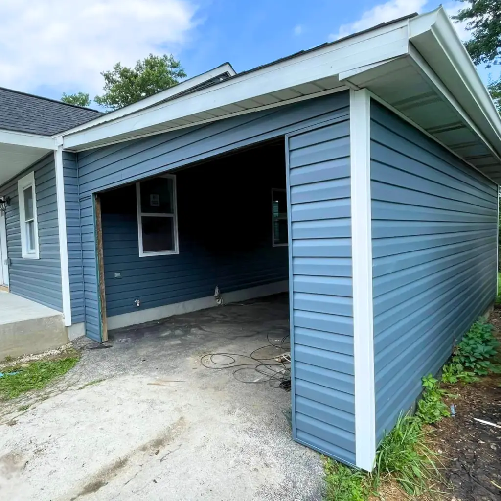 Newly installed blue vinyl siding on a residential garage.